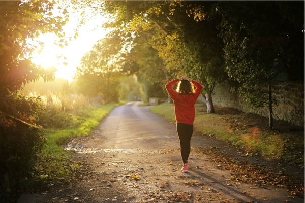 woman coping with anxiety by going for a walk down sunlit road | Perpetual Wellbeing