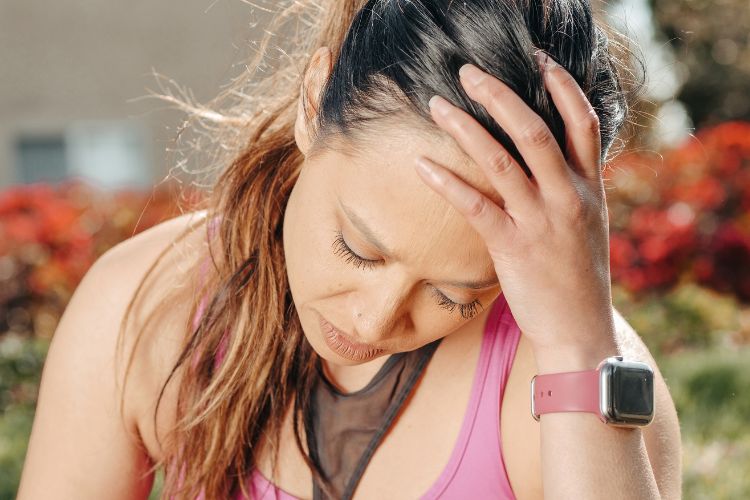 woman with eyes closed and head resting in her hand used on a blog about menstrual migraine headaches