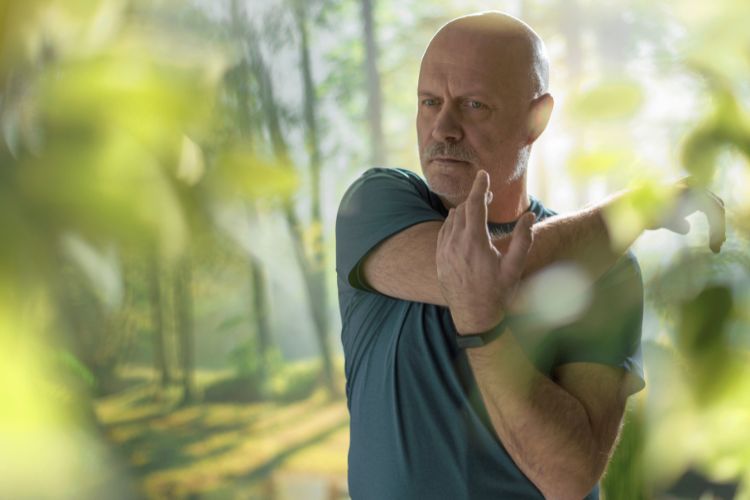 man stretching shoulder srrounded by trees used on a blog about men's health checks available without a full consultation