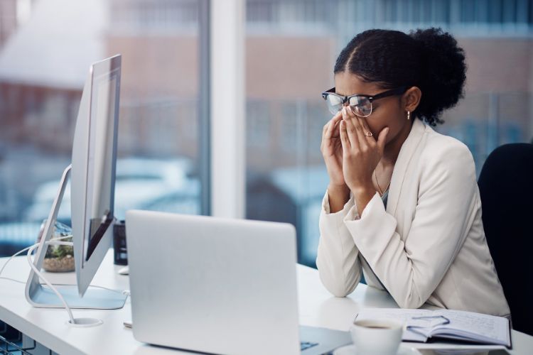 woman rubbing her eyes with laptop used on a blog about end of year burnout