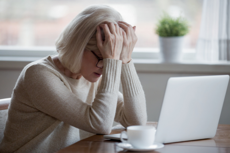 middle aged woman in front of a laptop with her forehead in her hands used on a blog about hormone replacement therapy