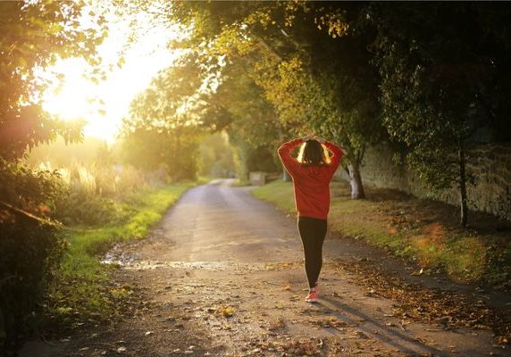 woman coping with anxiety by going for a walk down sunlit road | Perpetual Wellbeing