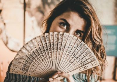 what causes hot flushes | woman with a fan | Perpetual Wellbeing