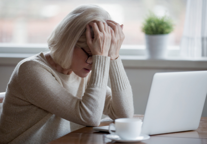 middle aged woman in front of a laptop with her forehead in her hands used on a blog about hormone replacement therapy
