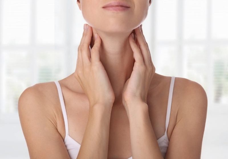 woman touching neck | signs and symptoms of thyroid issues | Perpetual Wellbeing