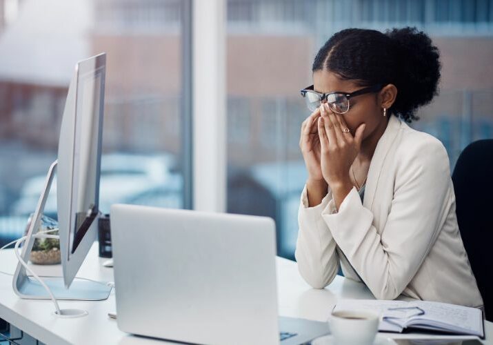 woman rubbing her eyes with laptop used on a blog about end of year burnout